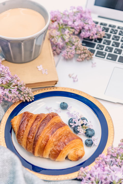 花で彩る朝食シーン、クロワッサンとノートパソコン