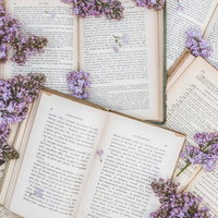 敷き詰められた洋書に散らばるライラックと読書の写真