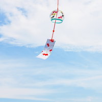 涼を味わう日本の夏、青空に吊るされた赤い風鈴の写真