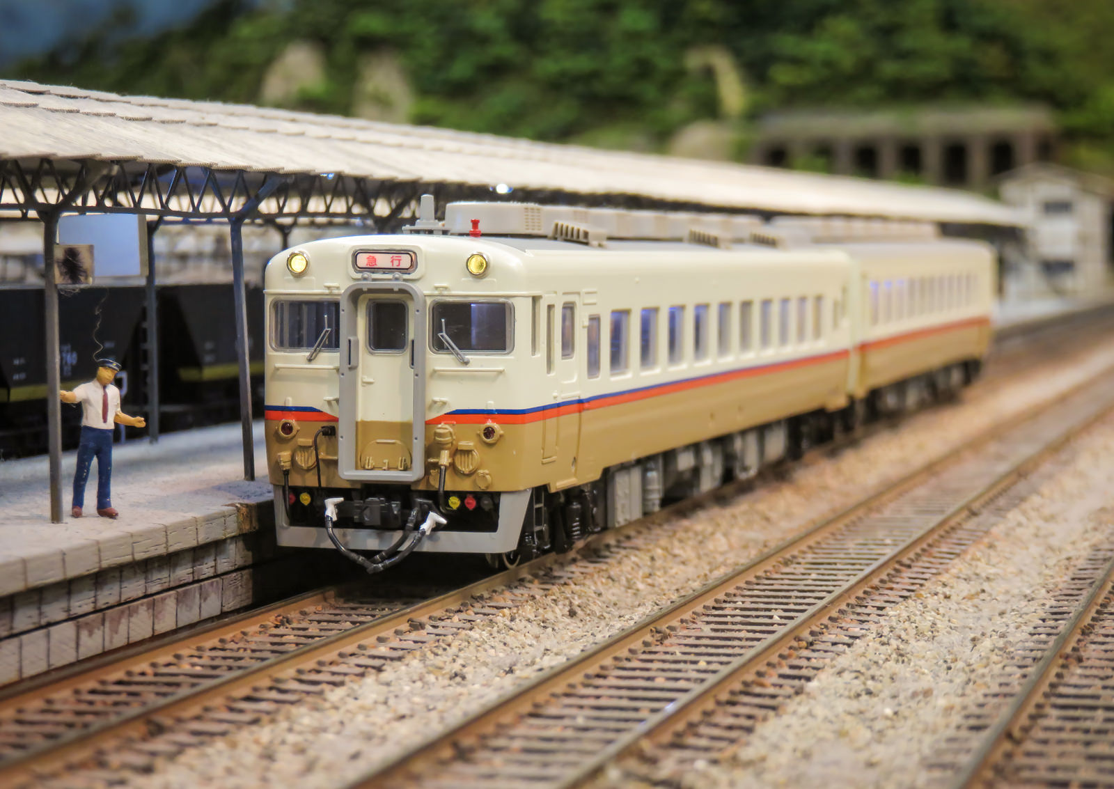 駅のホームに停車するオレンジと白のJR九州急行色キハ58・65形の鉄道模型