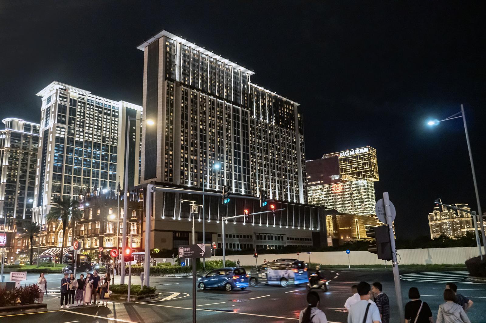 夜のマカオのホテル群がライトアップされ、観光客が歩く交差点の風景