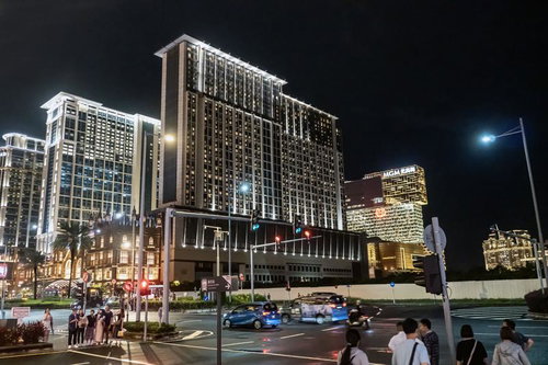 夜間にライトアップされたマカオのホテル群と観光客の町並み