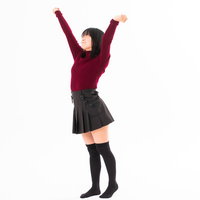 両手を伸ばして背伸びする赤いセーターの女性の写真