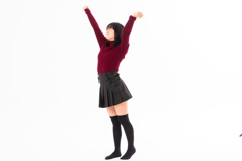 両手を伸ばして背伸びする赤いセーターの女性