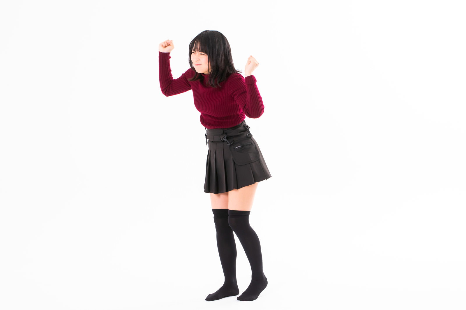 赤いトップスを着て両手で拳を作り怒りの表情を見せる女性［モデル：にゃるる］