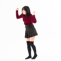 拳を振り上げて怒る女性、赤いトップスで怒りの表情の写真