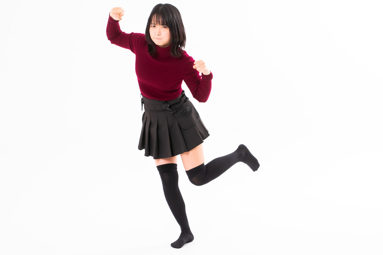 赤いセーターを着た女性が右手の拳を振り上げて怒りを表現している［モデル：にゃるる］