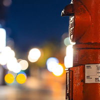 夜間の繁華街で光るネオンを背景にした赤い郵便ポストの写真