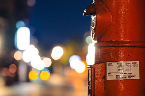 夜間の繁華街で光るネオンを背景にした赤い郵便ポスト
