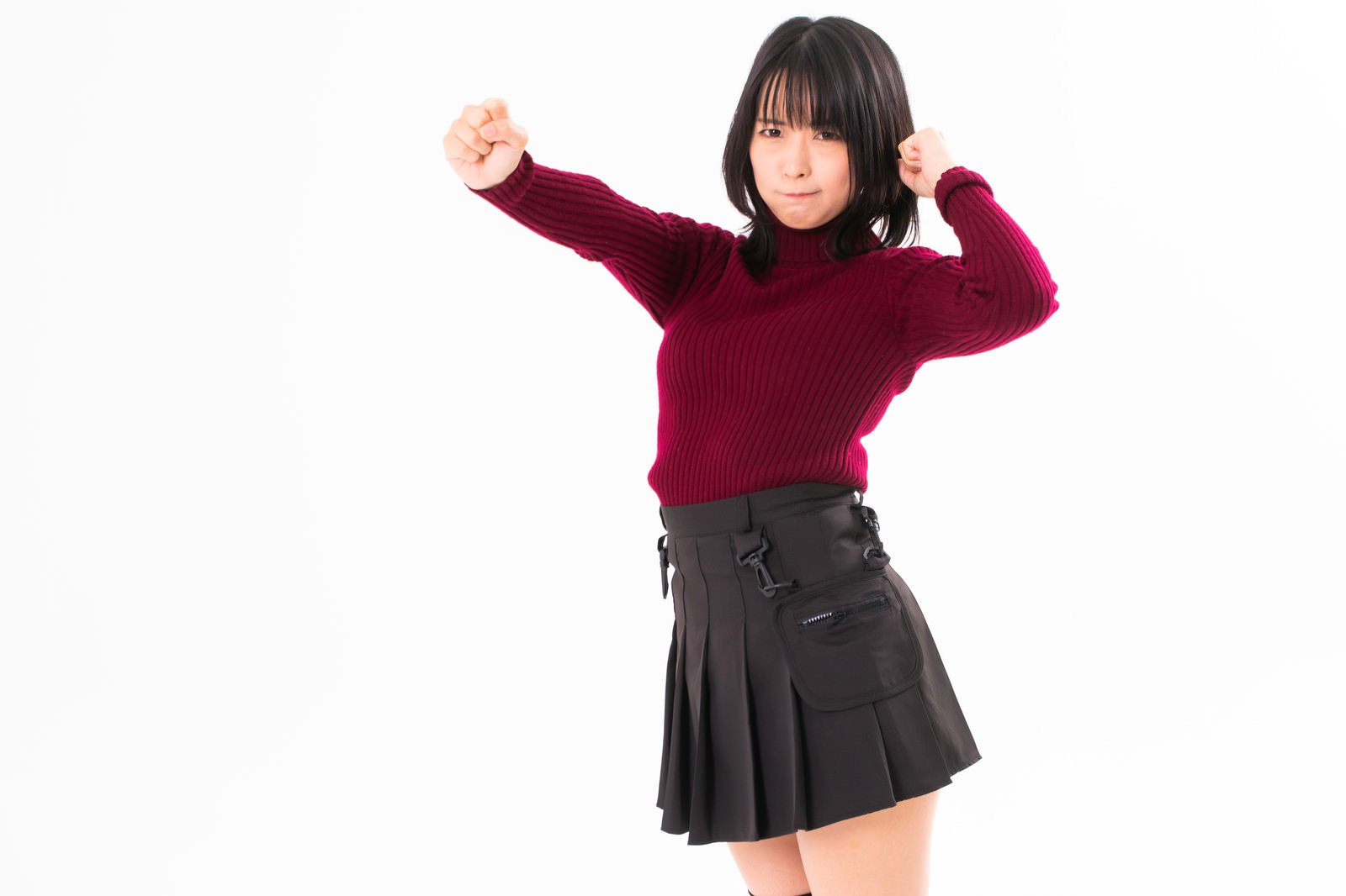 赤いセーターを着た女性が怒った表情で両手を上げている［モデル：にゃるる］