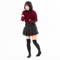 我慢して拳に力を込める赤トップスの女性のストレス表現の写真