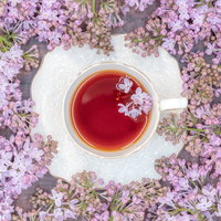 溢れるライラックに囲まれた白いティーカップと紅茶の写真