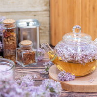 ティーポットから溢れるライラックの花とティーセットの写真