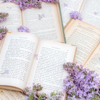 紫のライラックと敷き詰められた洋書のテーブルの写真