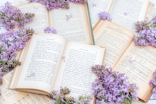 紫のライラックと敷き詰められた洋書のテーブル