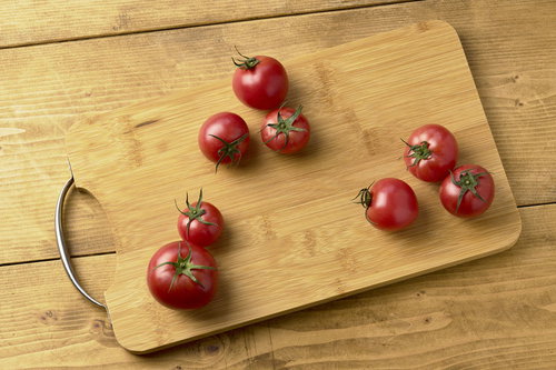 木製のまな板に並ぶ蔕付きミニトマト6個の新鮮な食材