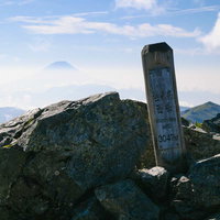 塩見岳西峰の山頂標識と遠くに見える富士山の写真