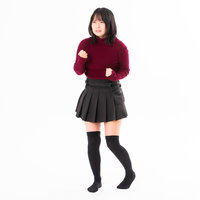 拳を握ってイライラする赤いニット姿の女性の写真