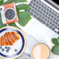 インスタントカメラと朝食のクロワッサン、モンステラのある朝のシーンの写真