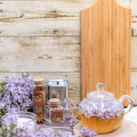 白い木目背景に並ぶライラックとティーポットの写真