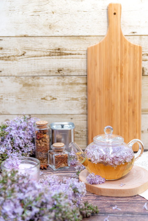 白い木目背景に並ぶライラックとティーポット