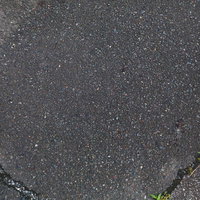 ひび割れたアスファルトと雑草が生える劣化した路面の写真