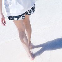 砂浜を歩く女性の足元、白いワンピース姿で夏の浜辺を散策の写真