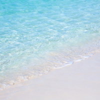 透き通る海と白砂の波打ち際、エメラルド色の浅瀬の写真