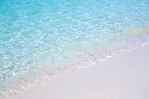 透き通る海と白砂の波打ち際、エメラルド色の浅瀬