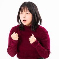 赤いセーターで両手を握りしめて応援に熱が入る女性の写真