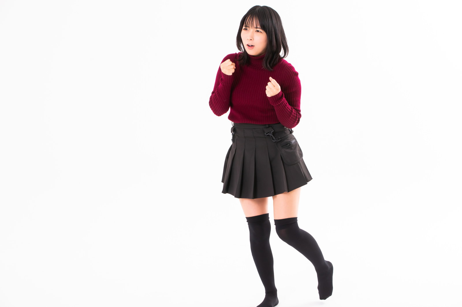 エンジ色のセーターを着た女性が両手を強く握りしめて怒りを我慢している様子［モデル：にゃるる］