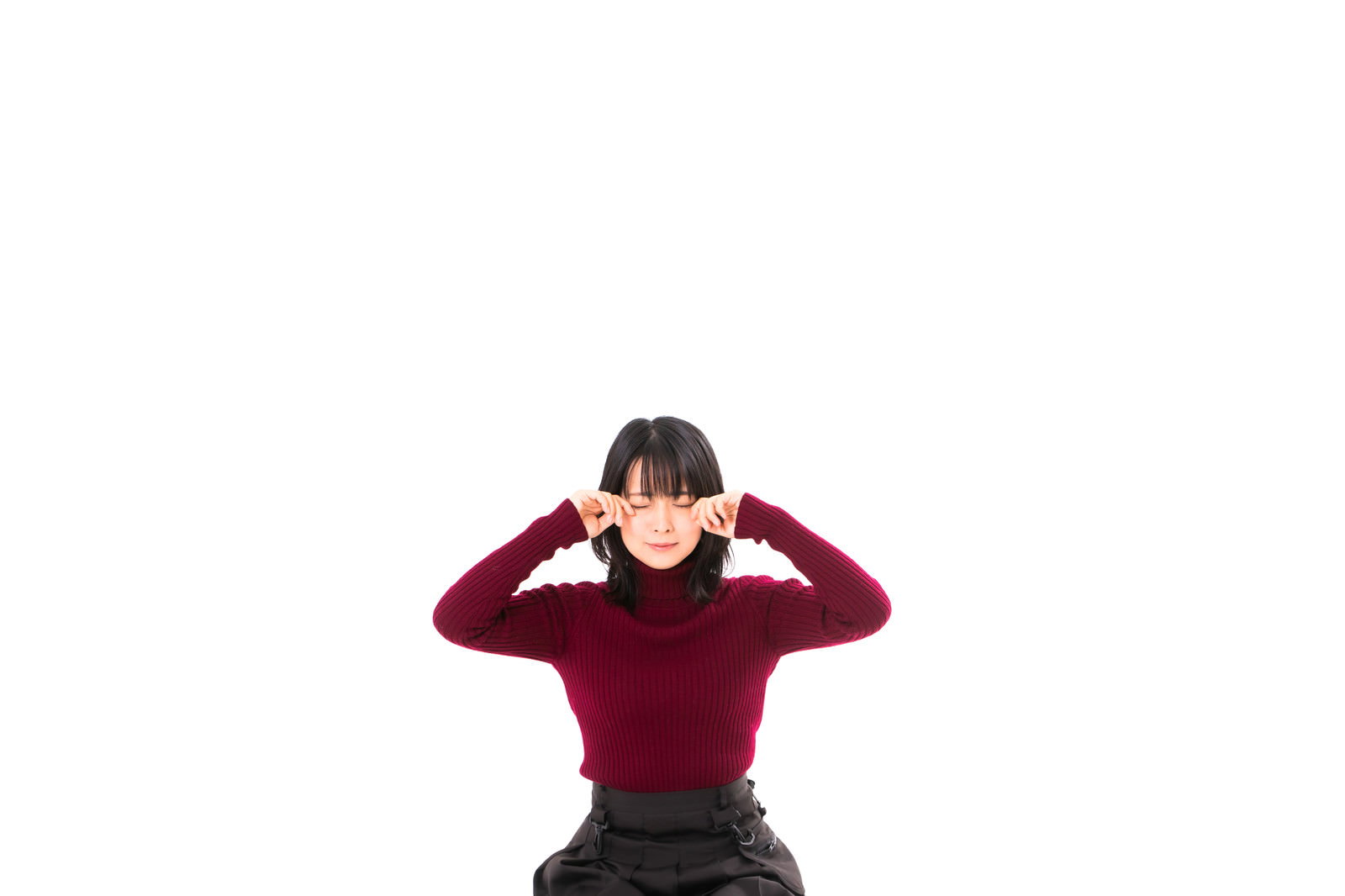 赤いニットを着た女性が両手で頭を抱えて落ち込んでいる様子［モデル：にゃるる］