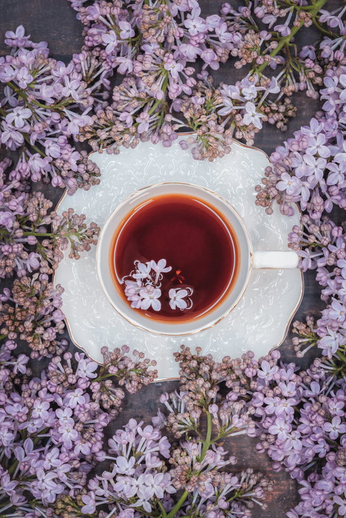 白いティーカップの紅茶に浮かぶライラックの花びら