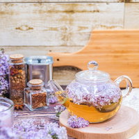 木製テーブルに置かれたライラック入りのティーポットの写真