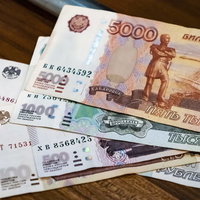 木製テーブルに無造作に置かれたロシアルーブルの紙幣の写真