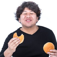 満面の笑みでハンバーガーを食べる男性の食事風景の写真