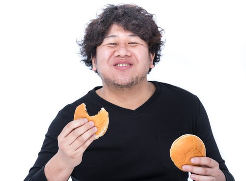 満面の笑みでハンバーガーを食べる男性の食事風景