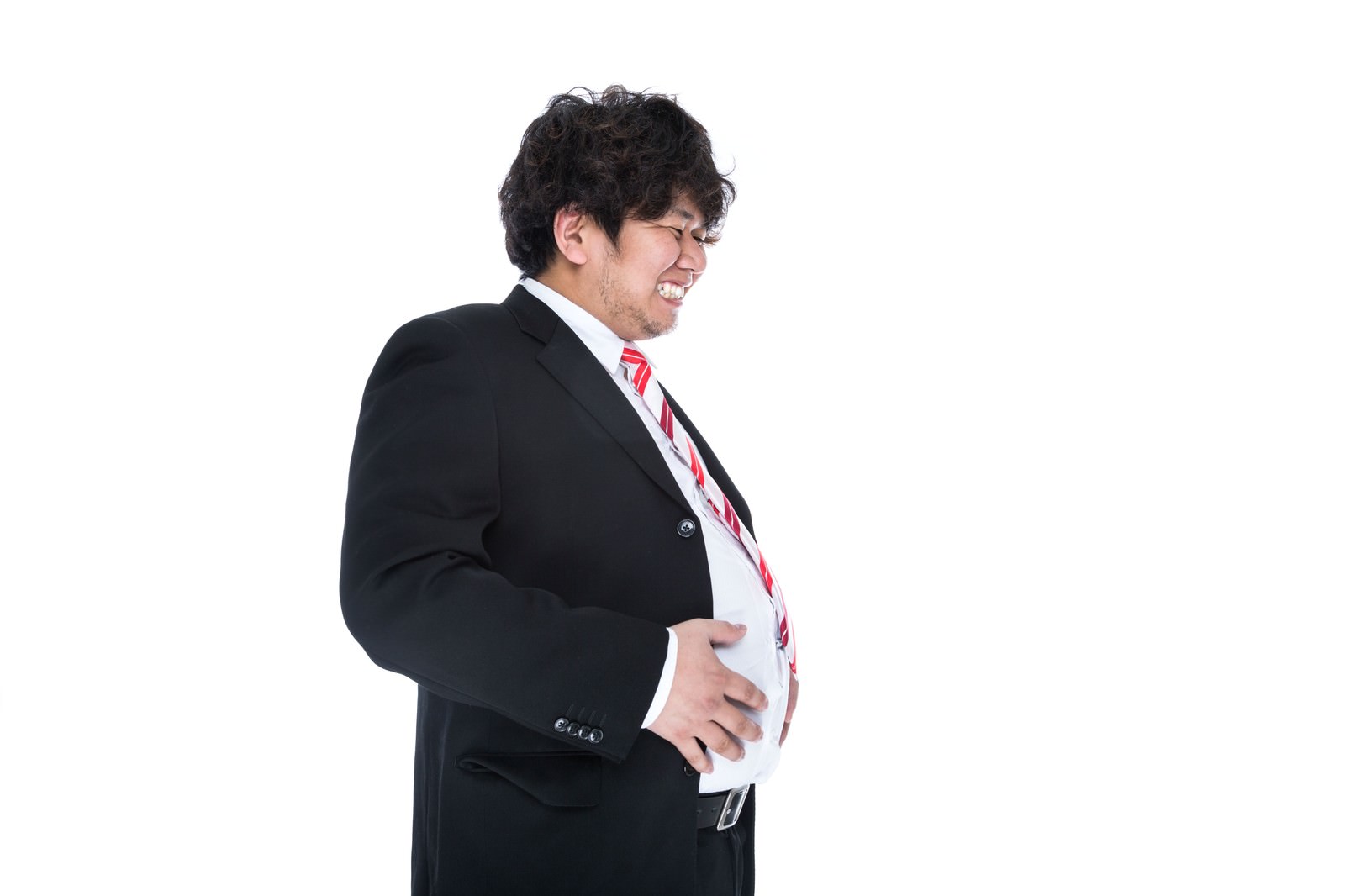 腹部に手を当てて笑う、メタボ体型のビジネスマンの男性［モデル：あまのじゃく］