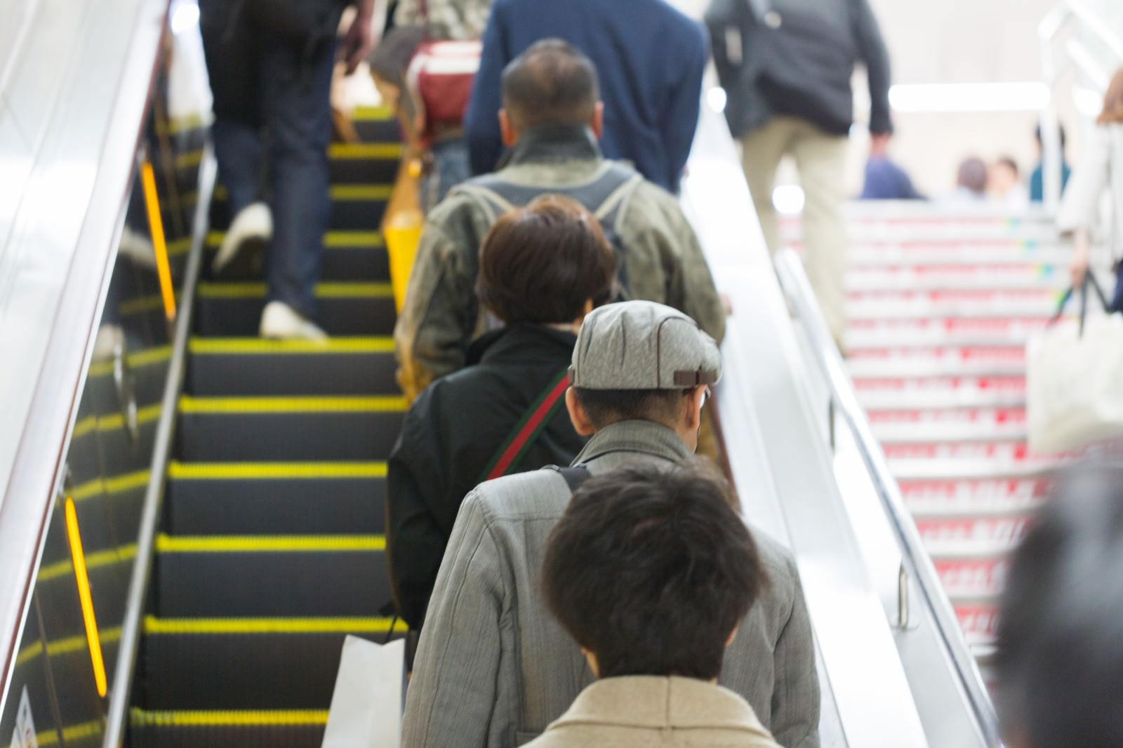 駅のエスカレーターに乗る複数の人が列をなしている光景
