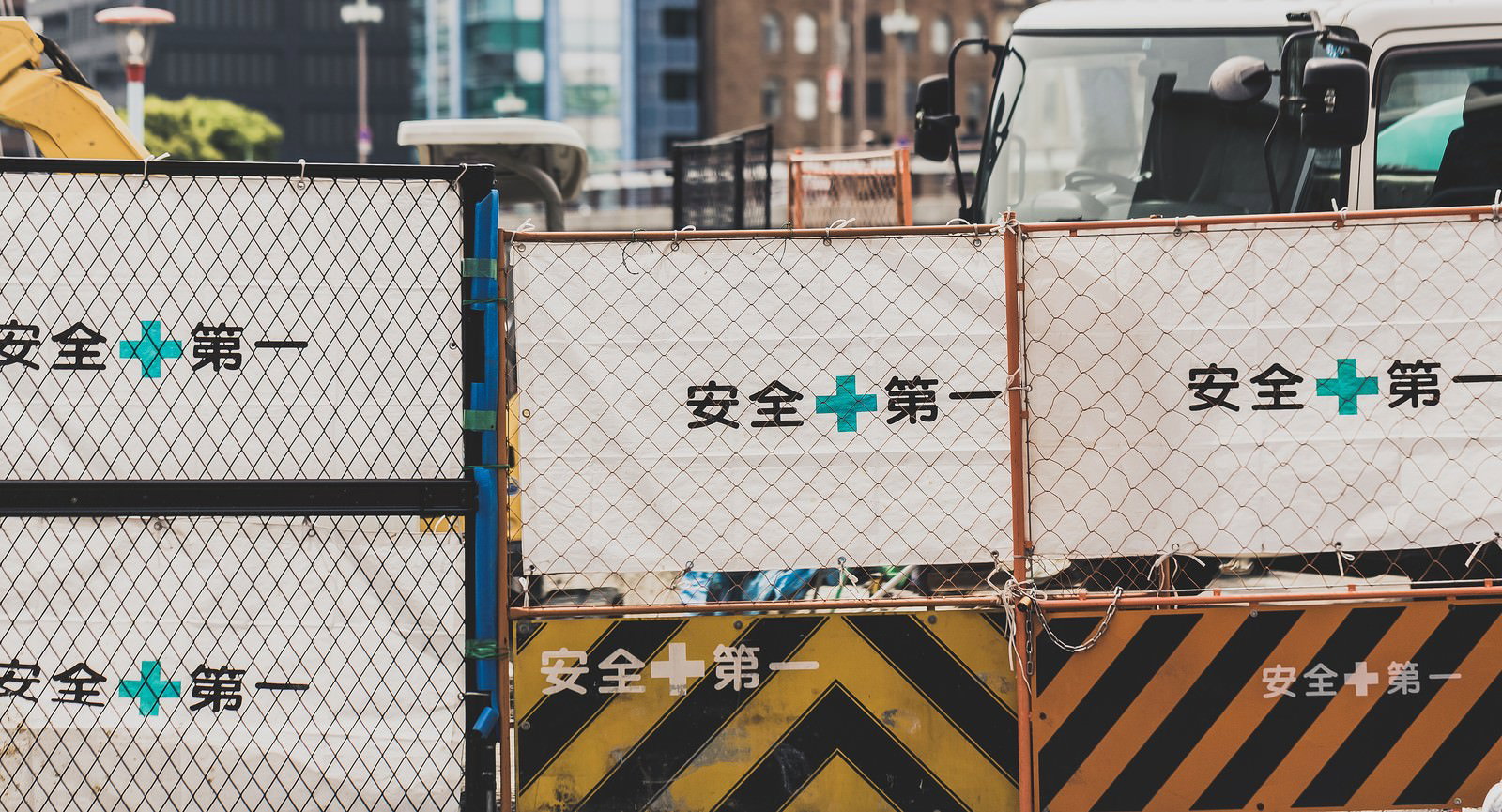 安全+第一と書かれたチェーンフェンスが張られた建設工事現場