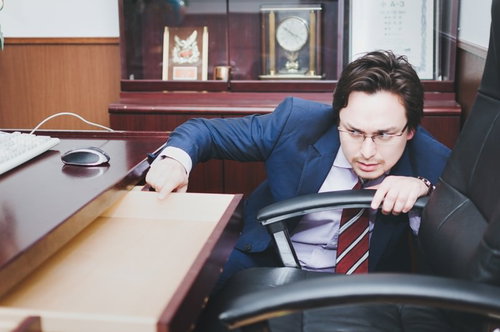 校長室の机で書類をチェックするハイスクール用務員