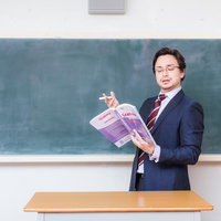 アメリカンジョークが通じないことに困惑する教師が教科書を手に黒板の前に立つの写真