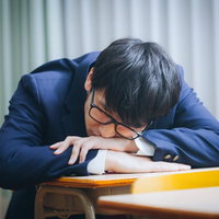 補習中に机に伏せて居眠りをする男性高校生の写真