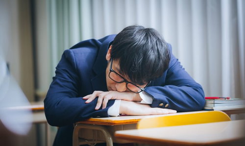 補習中に机に伏せて居眠りをする男性高校生