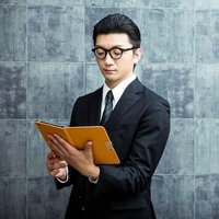 名簿をタブレットで確認する怪しい案内人の受付対応の写真