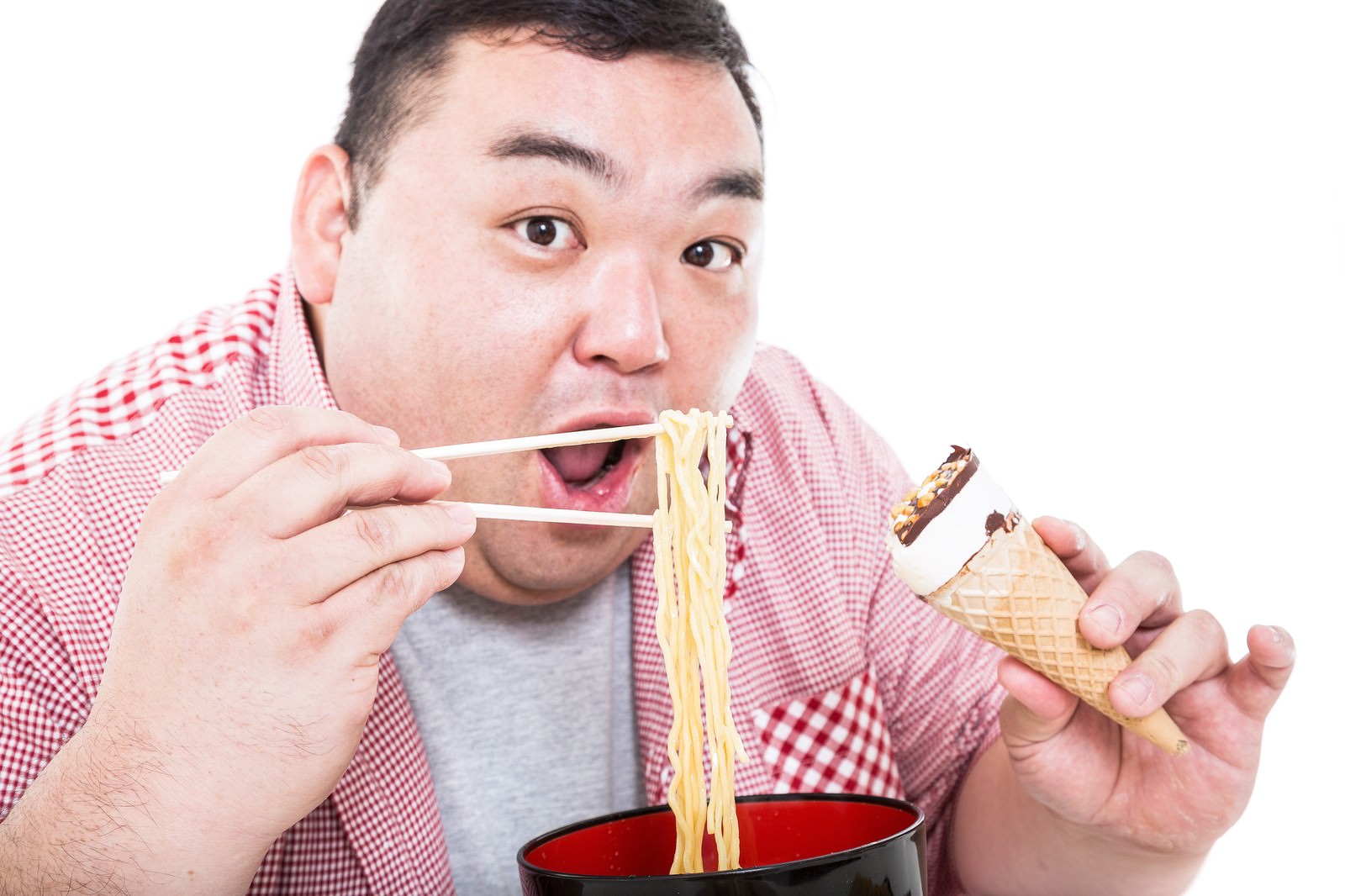 ラーメンを食べながらアイスを持つ男性［モデル：横山ともや］