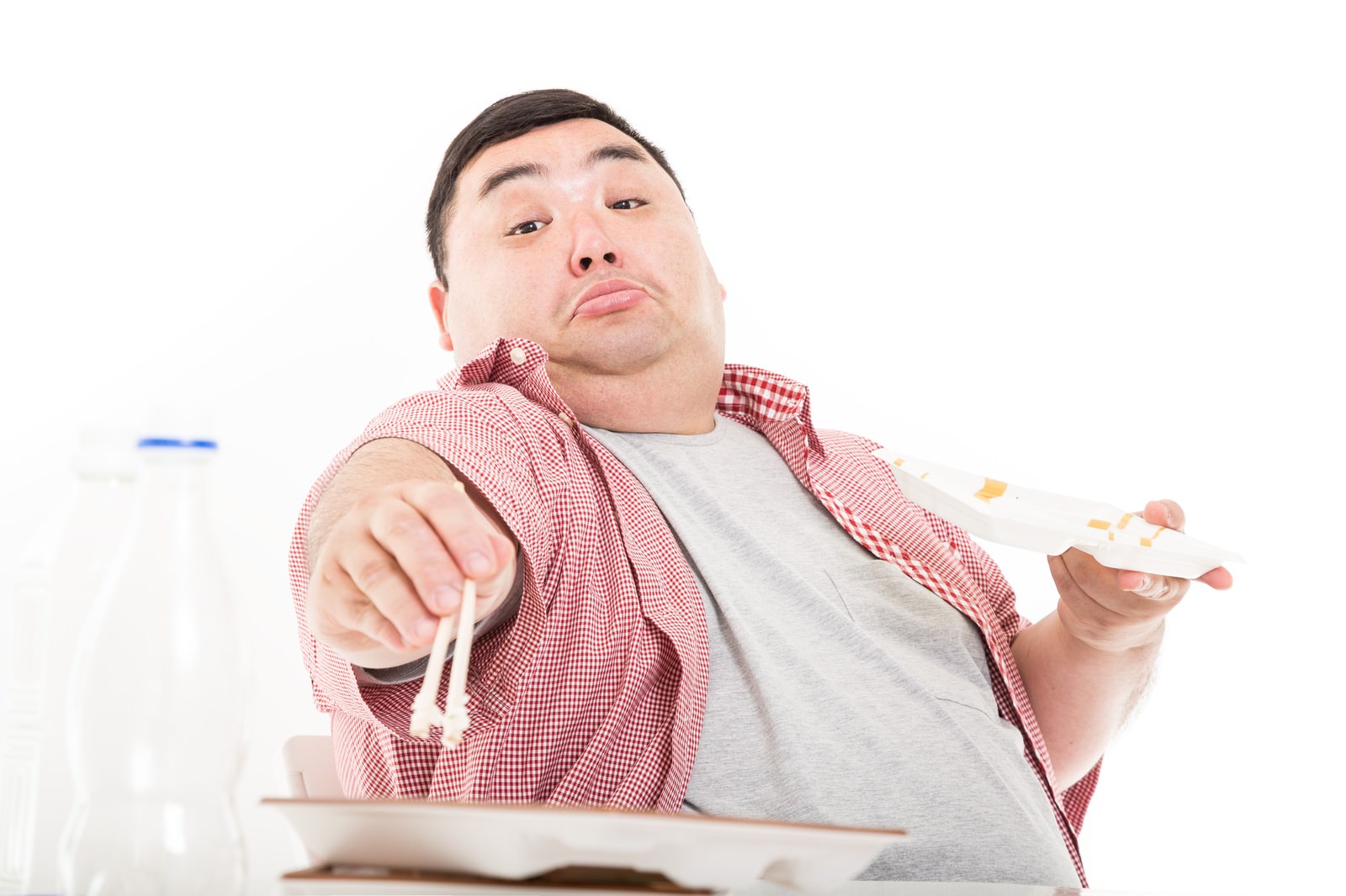 白い弁当を前に両手で箸を握る赤白ギンガムシャツの男性［モデル：横山ともや］