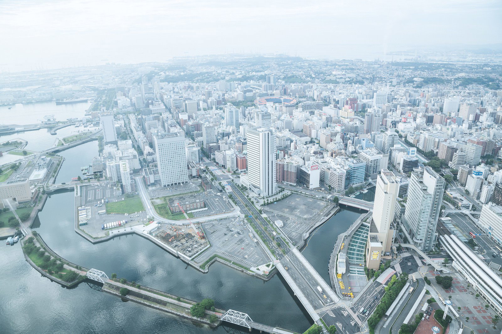 上空から見た横浜のビル群と街並み。河川に囲まれた駐車場と建物が密集している。
