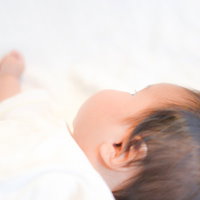 赤ちゃんの横顔と背景の大人の写真