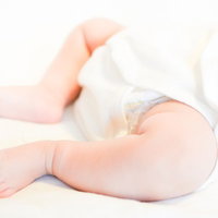 白いおむつを履いた赤ちゃんの足と新生児の肌の写真